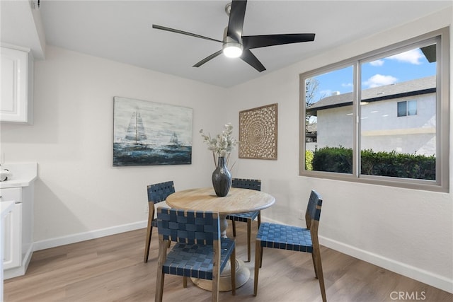 dining space featuring a ceiling fan, light wood-style flooring, and baseboards