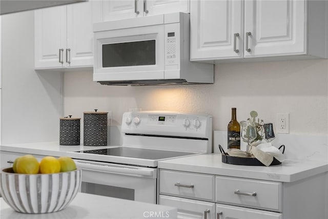 kitchen with light countertops, white appliances, and white cabinets