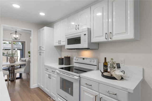 kitchen with recessed lighting, white appliances, white cabinets, light countertops, and light wood finished floors