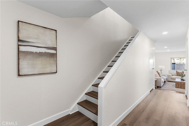 staircase featuring baseboards, wood finished floors, and recessed lighting