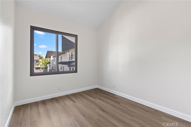 unfurnished room with lofted ceiling, wood finished floors, and baseboards