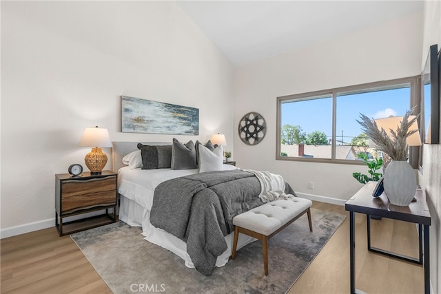 bedroom featuring high vaulted ceiling, baseboards, and wood finished floors