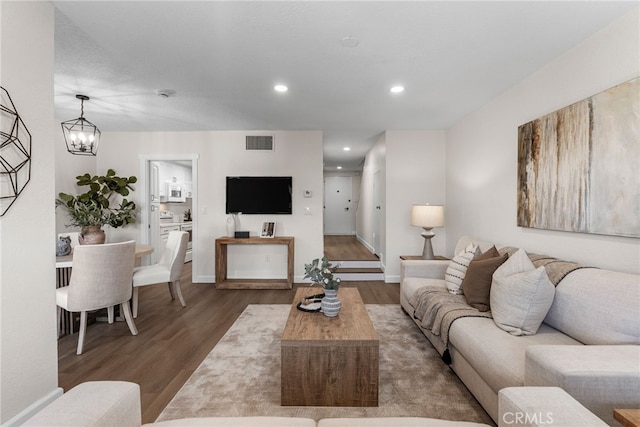 living room with recessed lighting, visible vents, an inviting chandelier, wood finished floors, and baseboards