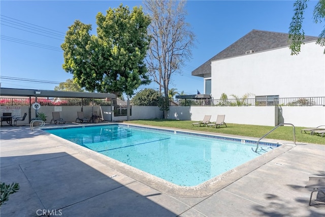 pool featuring a patio, a lawn, and fence