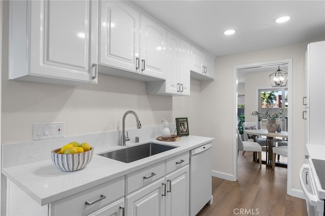 kitchen featuring white cabinets, range, dark wood-style flooring, white dishwasher, and a sink