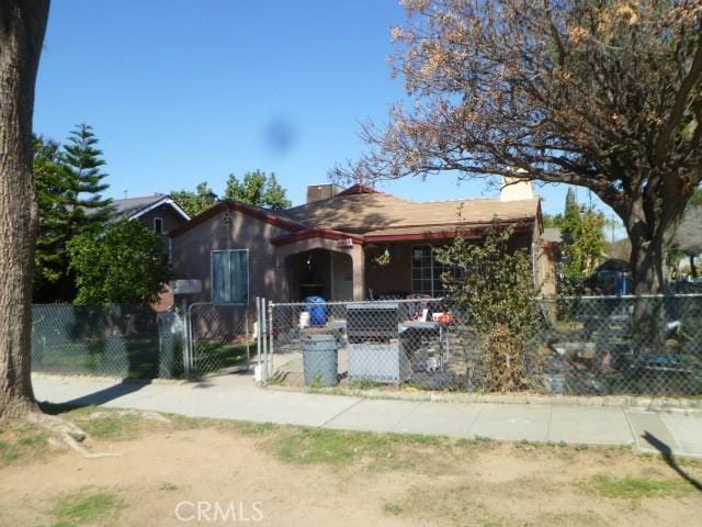 view of front of home with covered porch, a fenced front yard, a chimney, and a gate