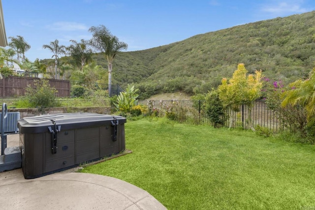 view of yard featuring a patio area, a hot tub, a mountain view, and a fenced backyard