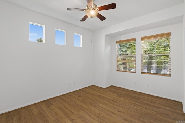 spare room with wood finished floors, a ceiling fan, and baseboards