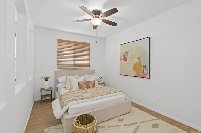 bedroom featuring a ceiling fan, baseboards, and wood finished floors