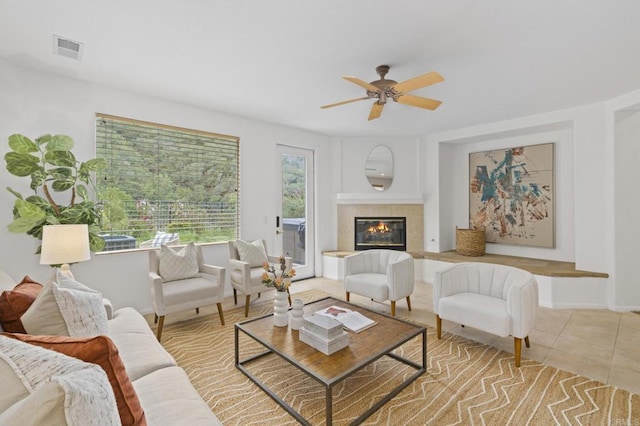 living area with a fireplace, visible vents, ceiling fan, tile patterned flooring, and baseboards