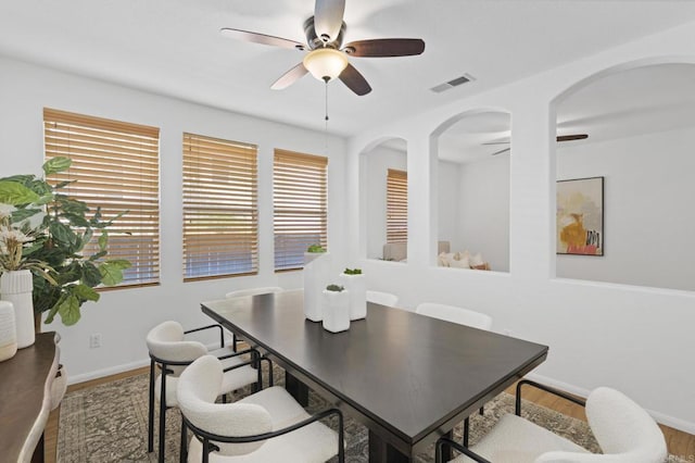 dining room featuring a ceiling fan, visible vents, baseboards, and wood finished floors