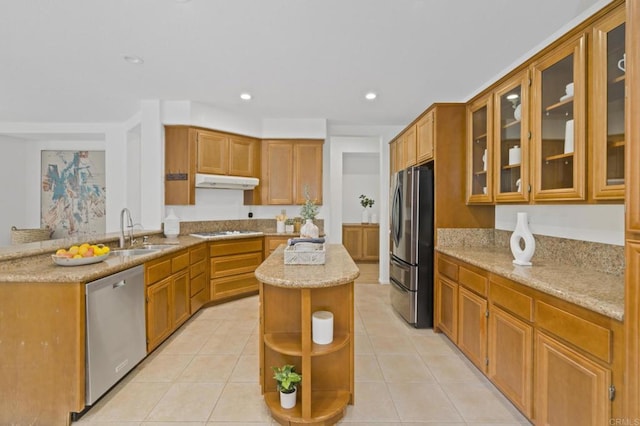 kitchen with appliances with stainless steel finishes, light stone countertops, under cabinet range hood, a sink, and light tile patterned flooring