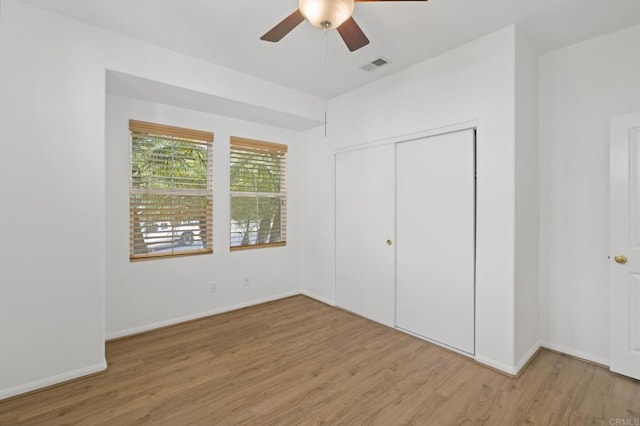 unfurnished bedroom with baseboards, visible vents, a ceiling fan, wood finished floors, and a closet