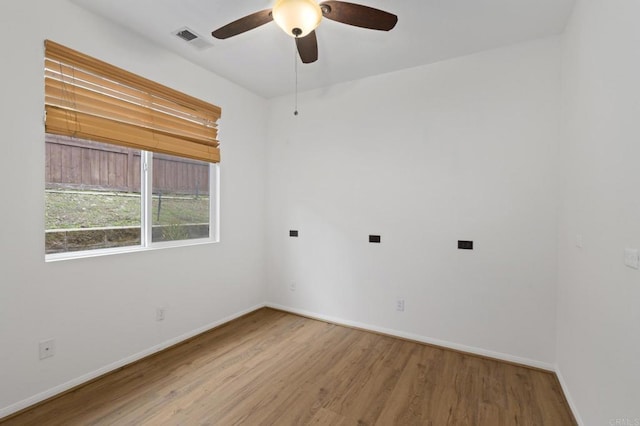 empty room with a ceiling fan, visible vents, baseboards, and wood finished floors