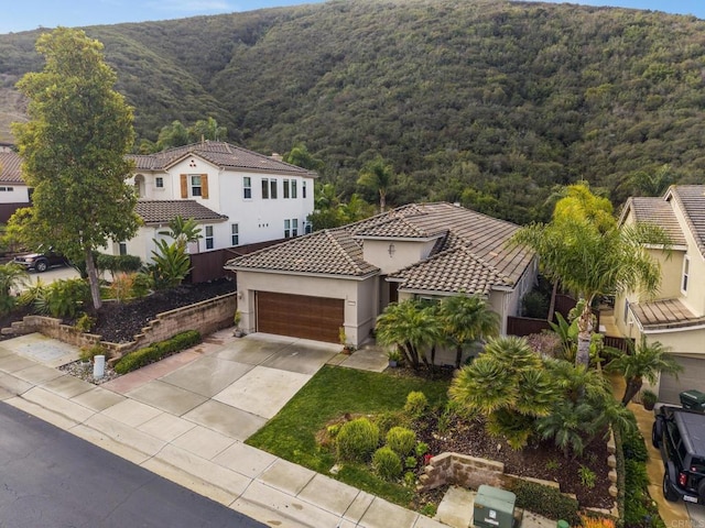 view of front of property with driveway, a tiled roof, a garage, and stucco siding