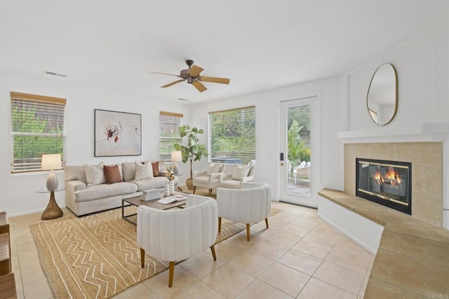 living room featuring ceiling fan, light tile patterned flooring, a fireplace, and visible vents