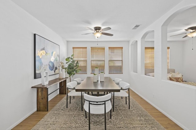 dining room featuring light wood finished floors, ceiling fan, visible vents, and baseboards