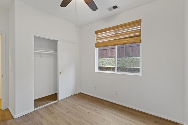 unfurnished bedroom featuring baseboards, a closet, visible vents, and wood finished floors