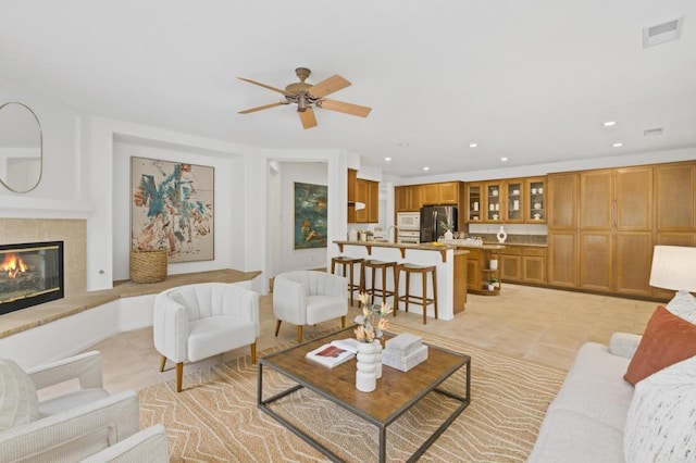 living room with light tile patterned floors, visible vents, a tiled fireplace, and recessed lighting