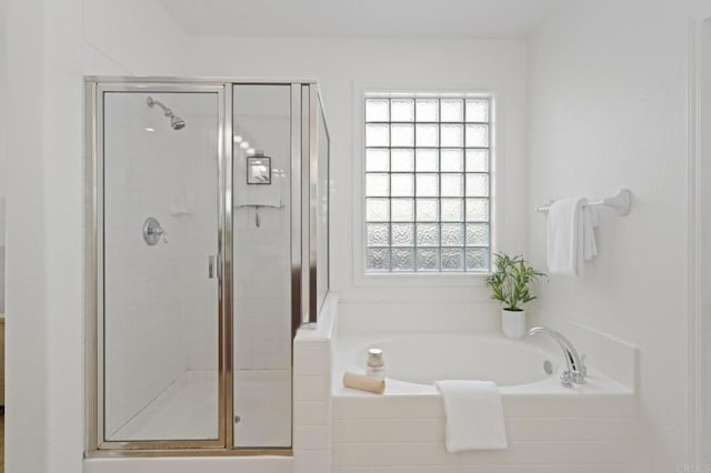 bathroom featuring a shower stall and a bath