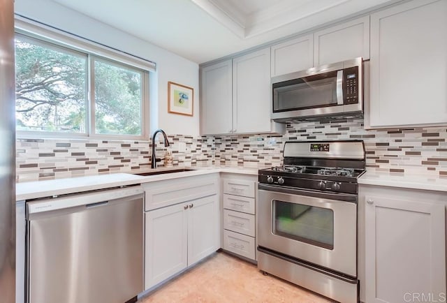 kitchen featuring backsplash, stainless steel appliances, a sink, and light countertops