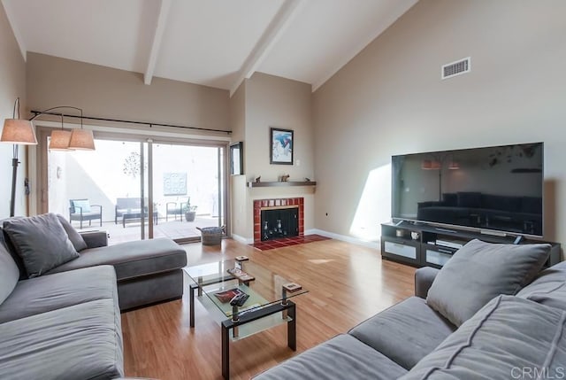 living area featuring high vaulted ceiling, beam ceiling, visible vents, and wood finished floors