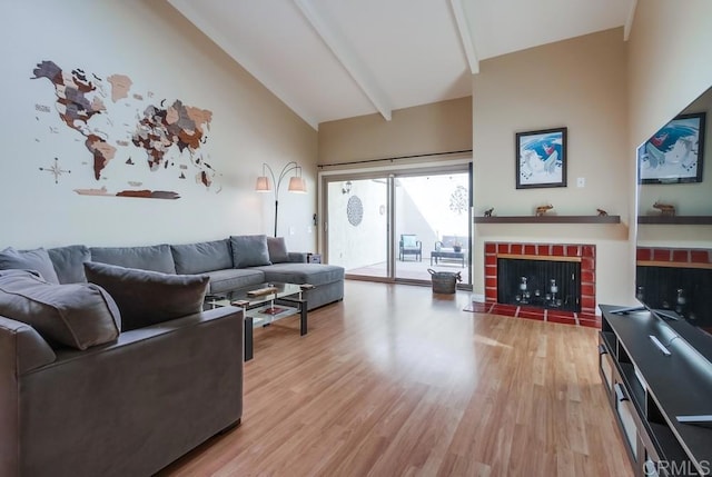 living area featuring high vaulted ceiling, light wood-type flooring, beam ceiling, and a brick fireplace