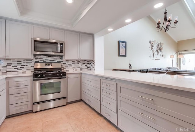 kitchen featuring tasteful backsplash, recessed lighting, gray cabinets, a raised ceiling, and appliances with stainless steel finishes