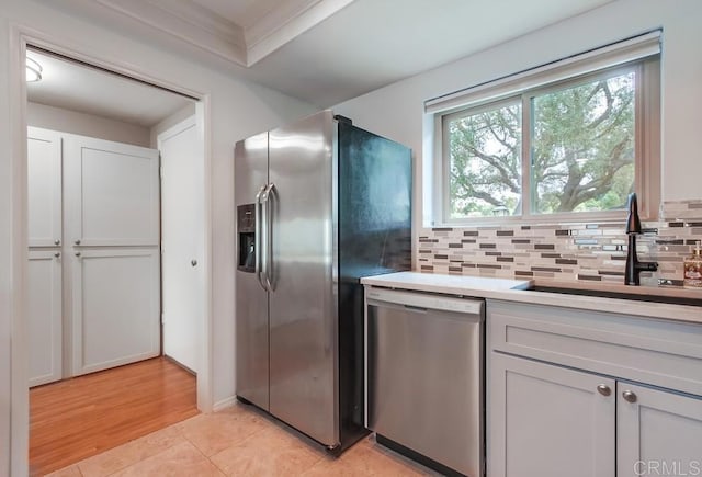 kitchen featuring stainless steel appliances, light countertops, a sink, and backsplash