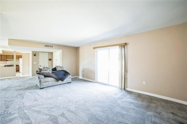 carpeted living area featuring visible vents and baseboards