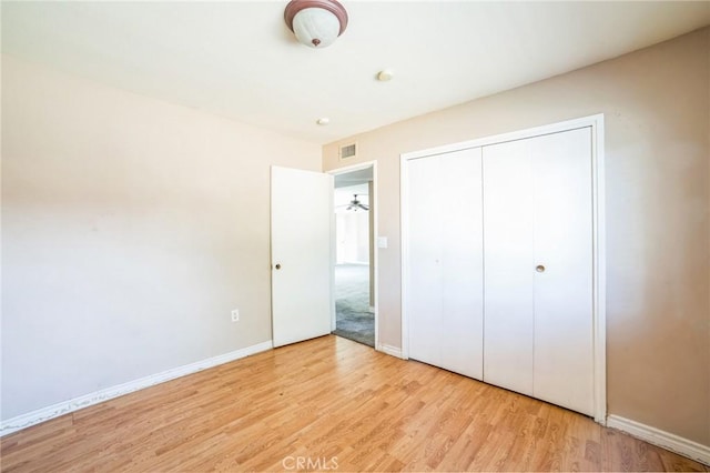 unfurnished bedroom with visible vents, a closet, baseboards, and wood finished floors