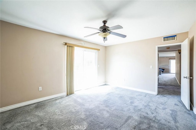 empty room with carpet, visible vents, ceiling fan, and baseboards