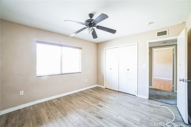 unfurnished bedroom with a closet, light wood-type flooring, visible vents, and baseboards