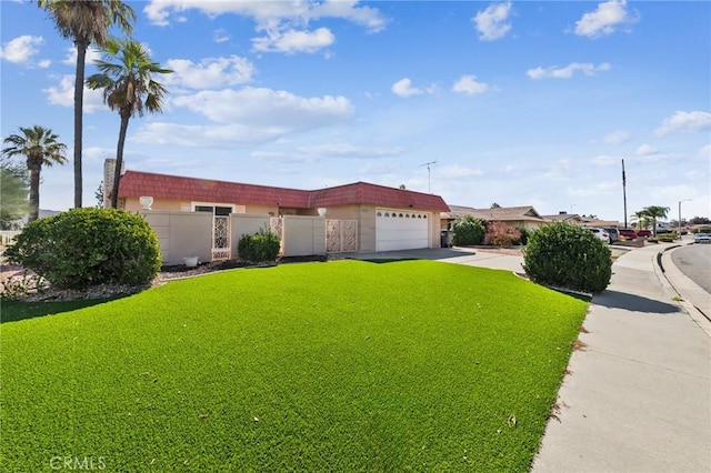 view of front of house featuring a front lawn, concrete driveway, fence, and an attached garage