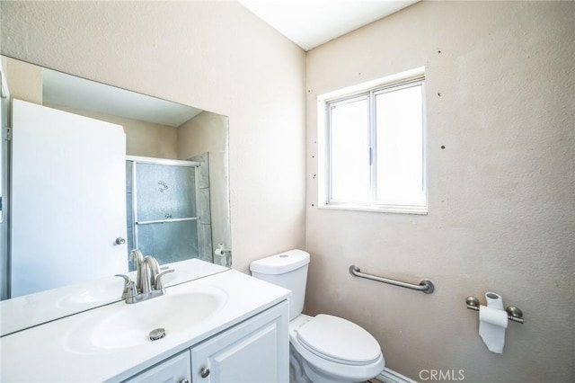 full bath featuring toilet, a stall shower, and vanity