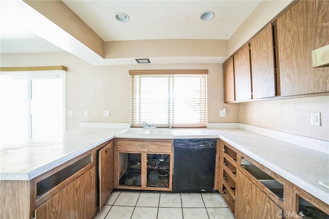 kitchen featuring light tile patterned floors, a sink, black dishwasher, light countertops, and brown cabinets