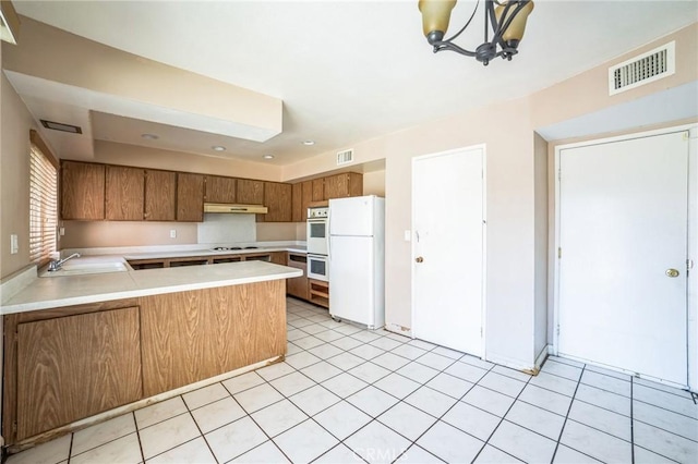 kitchen featuring white appliances, visible vents, light countertops, and a sink