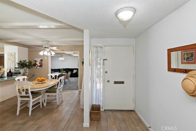 foyer featuring a ceiling fan, baseboards, a textured ceiling, and wood tiled floor