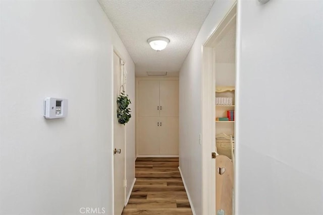 hallway with light wood-style floors and a textured ceiling