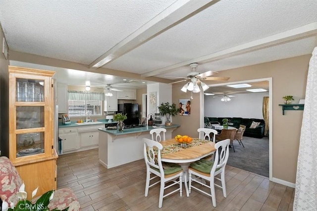 dining area featuring wood finish floors, beam ceiling, a textured ceiling, and a ceiling fan