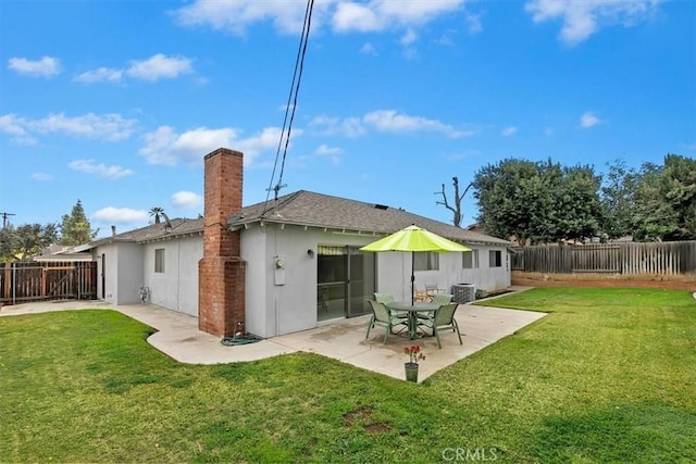 rear view of property featuring roof with shingles, stucco siding, a yard, a fenced backyard, and a patio area