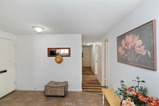 corridor with baseboards, a textured ceiling, and wood tiled floor