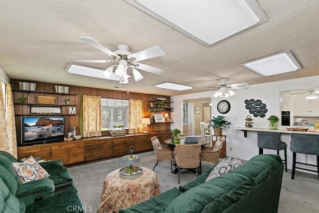 carpeted living room with a textured ceiling, a skylight, and a ceiling fan