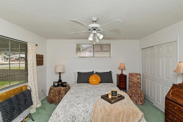 bedroom with a ceiling fan, carpet, a closet, and a textured ceiling