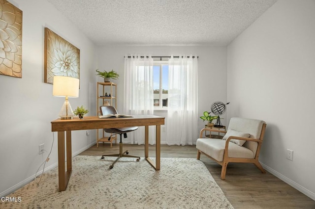 office area with baseboards, a textured ceiling, and wood finished floors