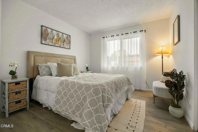 bedroom with wood finished floors, baseboards, and a textured ceiling