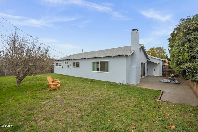 back of house with stucco siding, fence, a yard, a chimney, and a patio area