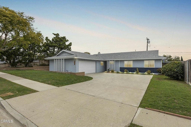 single story home with a garage, concrete driveway, a front yard, and stucco siding