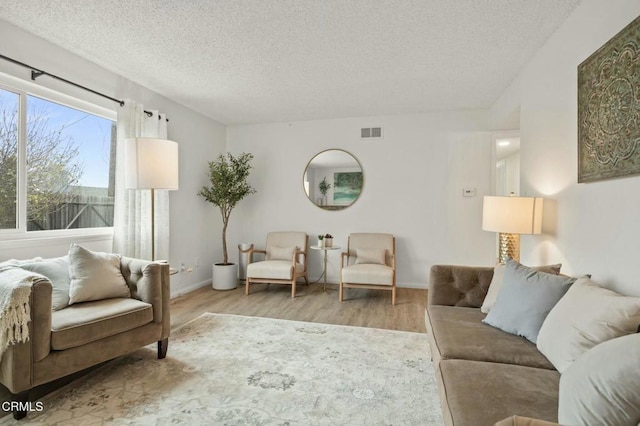 living room featuring visible vents, a textured ceiling, and wood finished floors