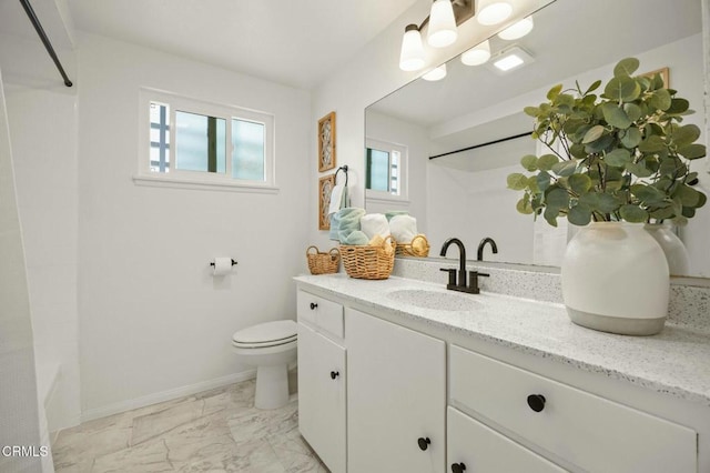 full bathroom with toilet, marble finish floor, vanity, and a healthy amount of sunlight